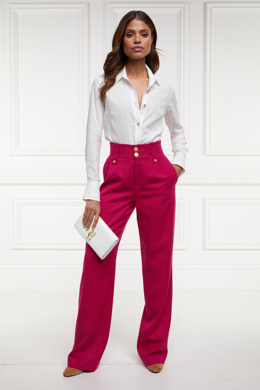 Women's hot pink wool high waisted straight trousers with classic white shirt and white croc clutch bag