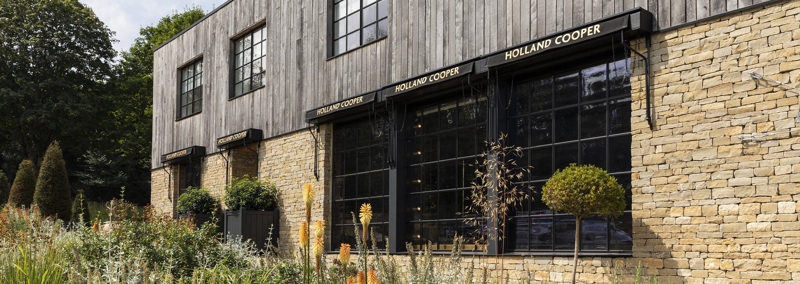 Holland Cooper Womens Boutique Store with gold lettering and cotswold yellow stone building with black glass windows