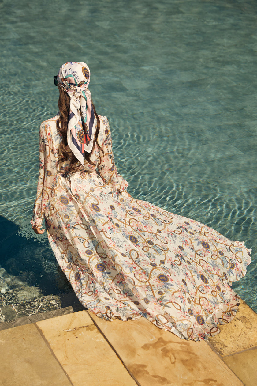 back shot of womens printed white maxi dress and white and pink scarf around her head