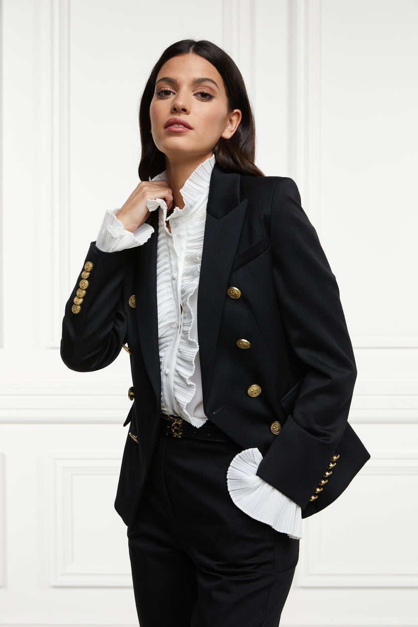 British made double breasted blazer that fastens with a single button hole to create a more form fitting silhouette with two pockets and gold button detailing this blazer is made from black barathea worn with white shirt and black tailored trousers