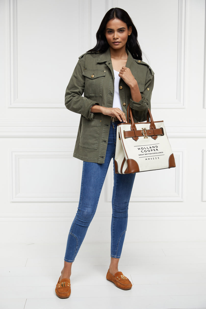 khaki green cotton womens shacket with blue denim jeans and cotton canvas womens tote bag with tan leather trims and handles with gold hardware and detachable keychain