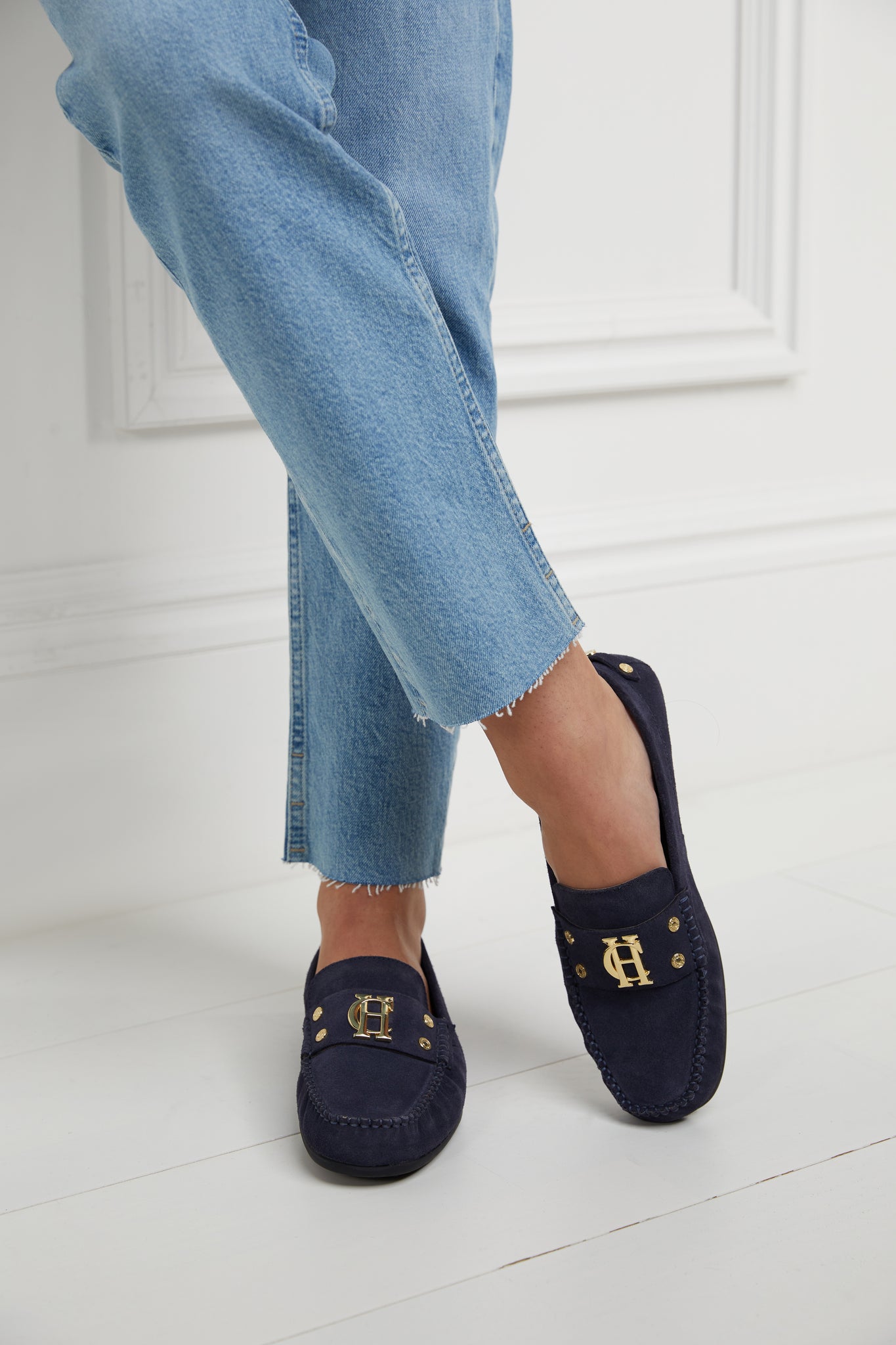 navy suede loafers with a leather sole and top stitching details and gold hardware paired with denim slim jeans