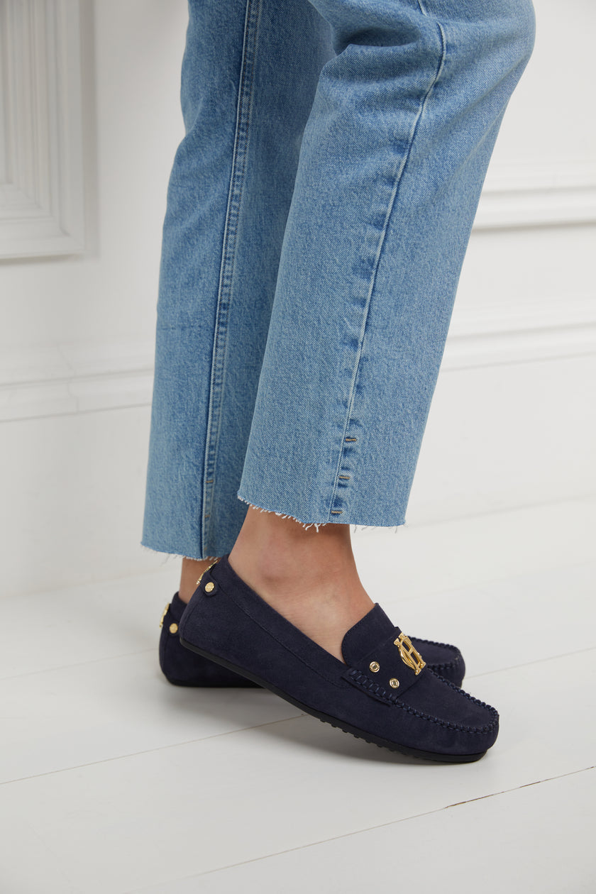 navy suede loafers with a leather sole and top stitching details and gold hardware paired with denim slim jeans