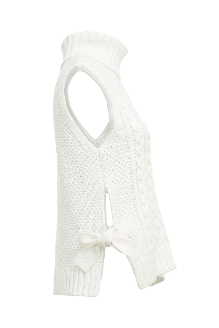 Side of sleeveless white chunky knit cable jumper with a roll neck and ties at each side 