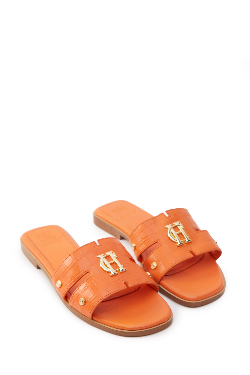 Side shot of orange croc embossed leather sliders with a tan leather sole and gold hardware. 